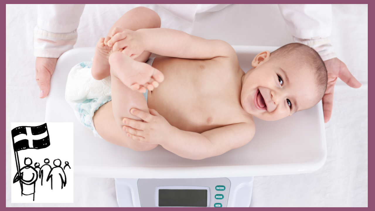 Smiling baby being weighed